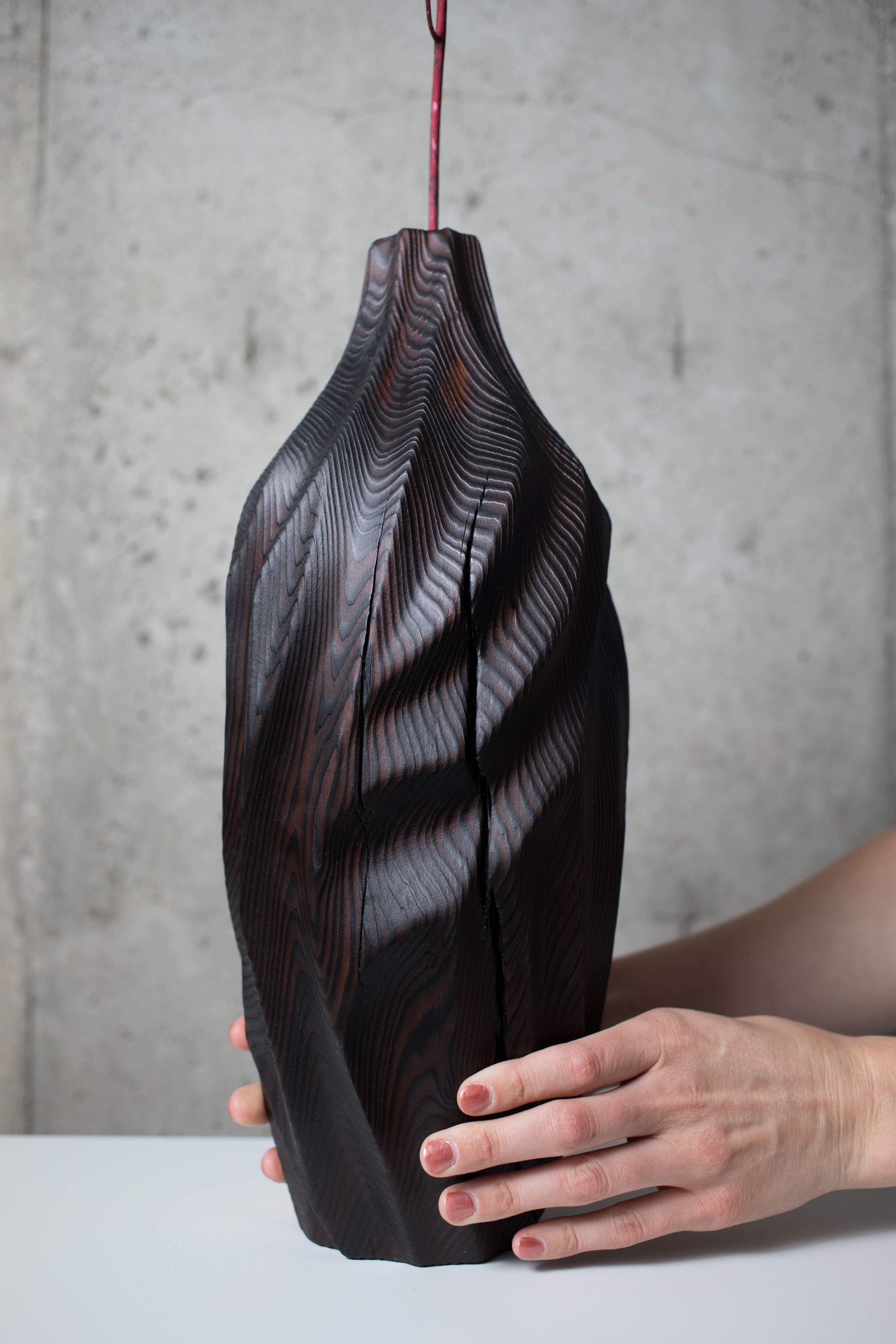 wooden vases to buy. Black sculpted vase held by artist.