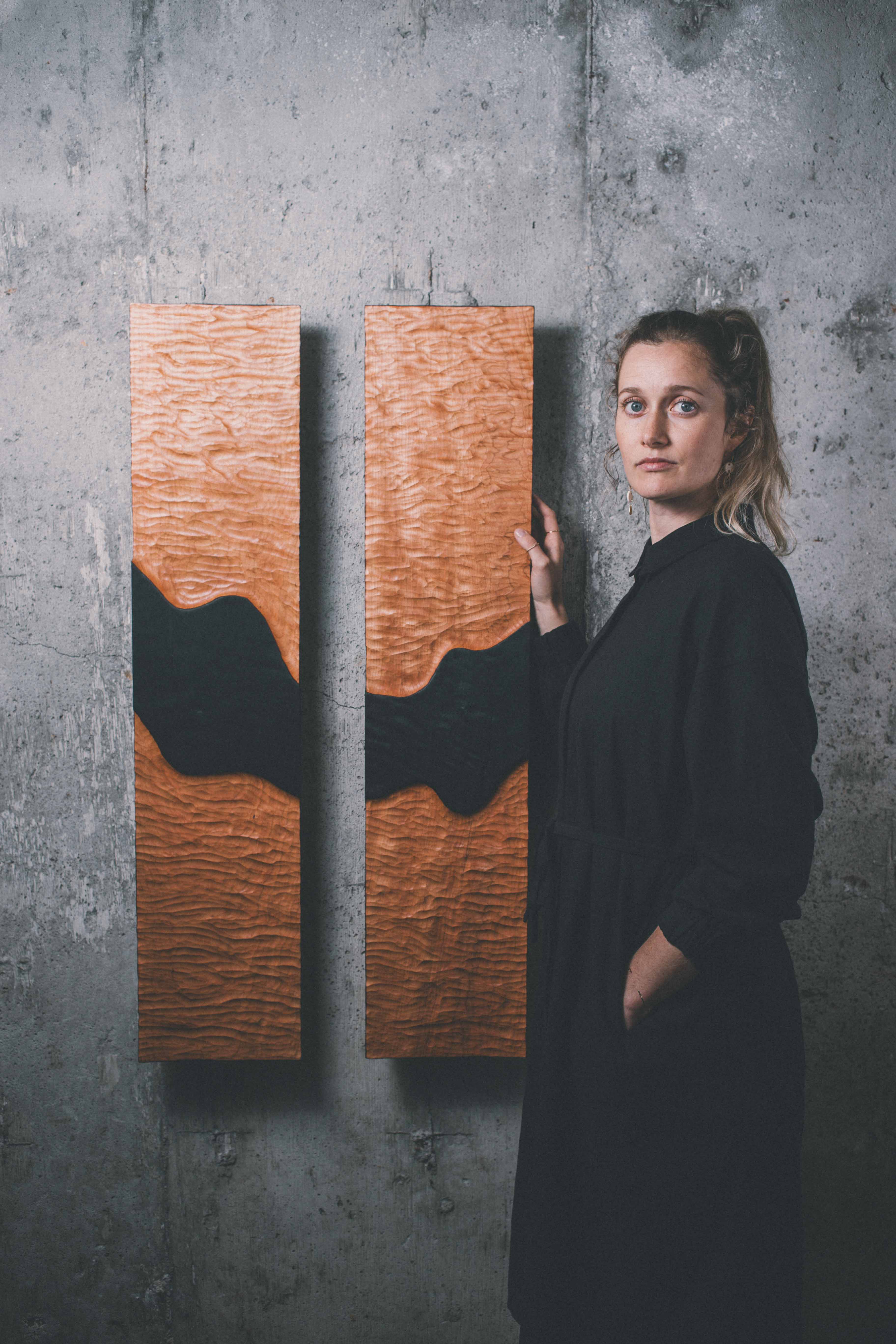 Artist Jackie Chapman stood next to her two-piece wooden modern decor wall art called Time Beings. 